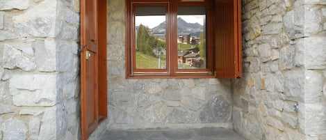 A stone-walled room with a window and wooden shutters.