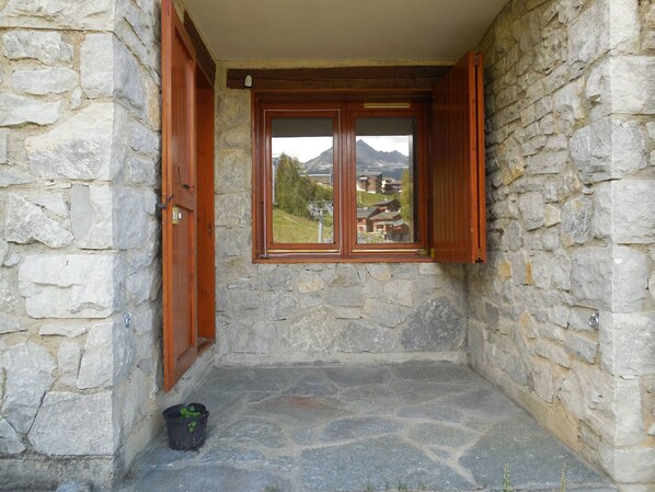 A stone-walled room with a window and wooden shutters. - Divisible studio for 4, direct slope access (La Plagne)