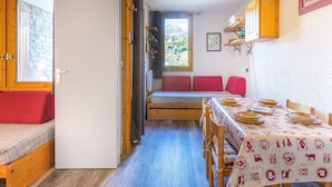 Una habitación acogedora con una cama, una mesa de comedor para dos personas y un banco con cojines.