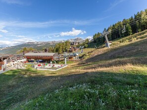 A ski resort with a mountain backdrop, including a ski lift and a building labeled "PLAN BOIS". - Divisible studio for 4, direct slope access (La Plagne)