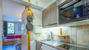 Cocina compacta equipada con microondas, lavaplatos y pileta. Una ventana permite ver el exterior.