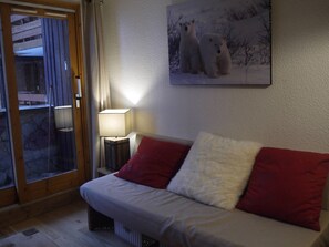A room with a bed, a lamp, a painting of polar bears, and a window with curtains.