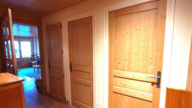 A hallway with wooden doors, a wooden desk, and a view into a room with a table and chairs. - Cozy 3-Room Apartment, South Exposure, Village Center, Sleeps 6 (La Clusaz)