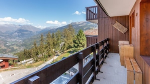 A wooden balcony with a view of a mountainous landscape.