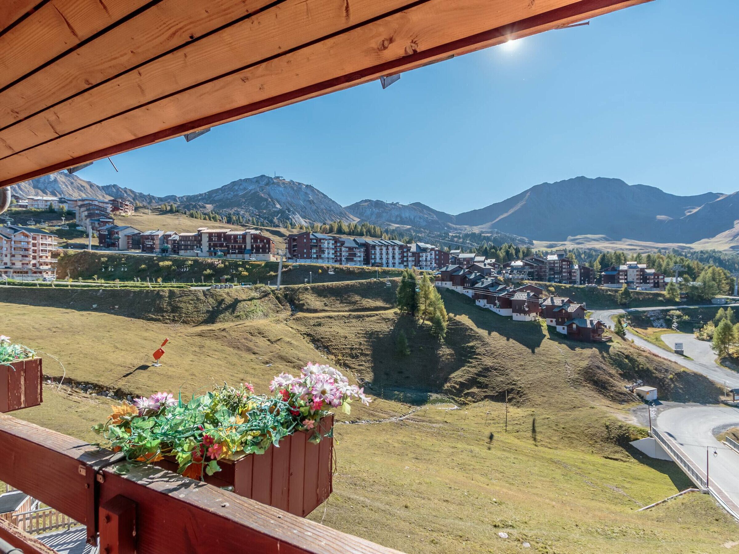 A view of a mountain resort with multiple buildings, a road, and a wooden structure with a flower planter.