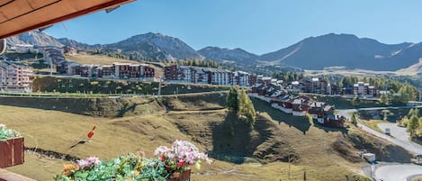 A view of a mountain resort with multiple buildings, a road, and a wooden structure with a flower planter.