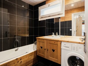 Une salle de bain moderne avec un meuble-lavabo en bois, un lave-linge encastré et un grand miroir.