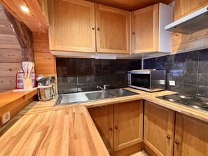 A kitchen with wooden cabinets, a black tiled backsplash, a stainless steel sink, and a built-in microwave. - Duplex 6 pers, central location, parking, pets OK (La Plagne)