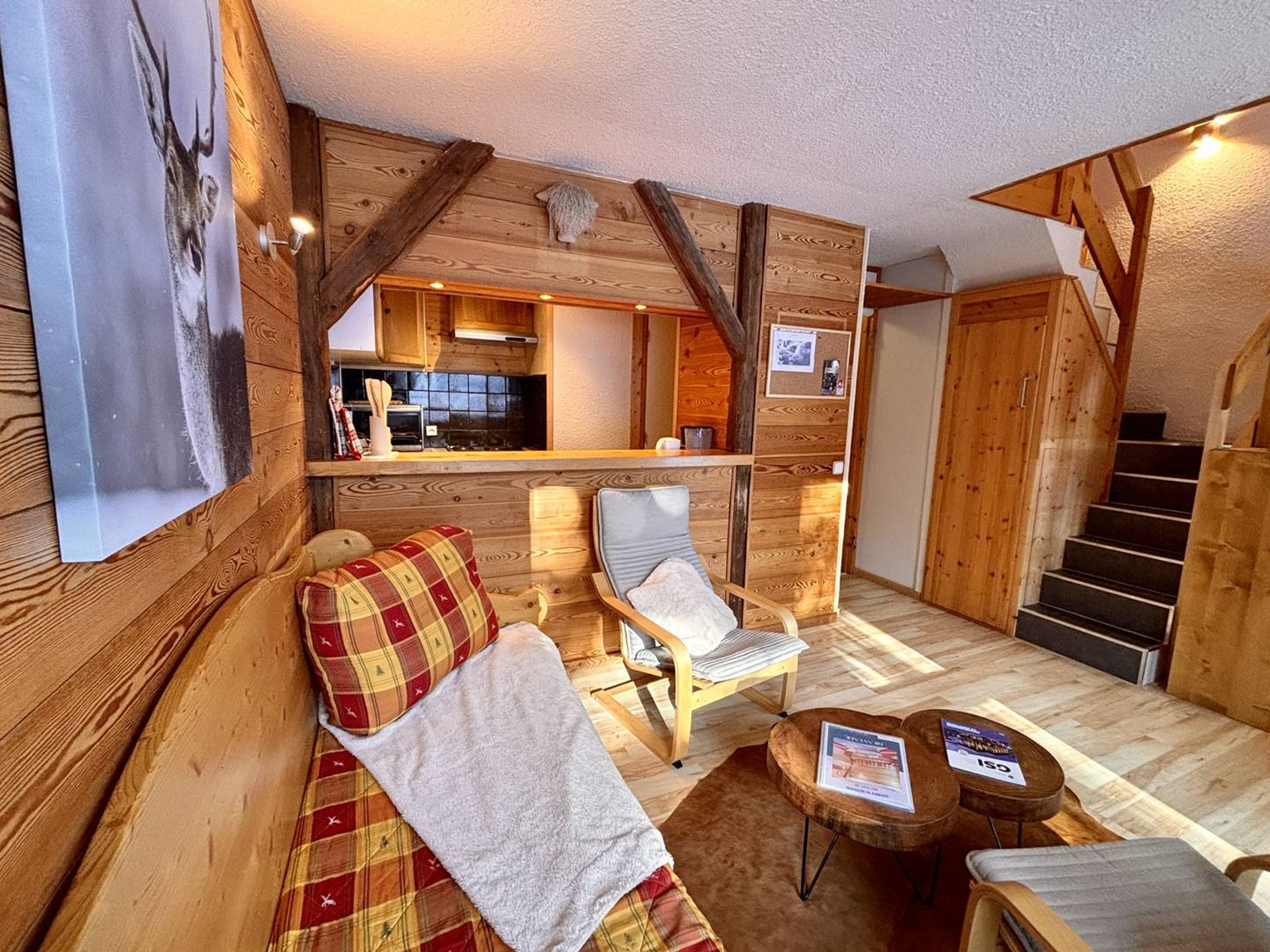 En hyggelig hyttekrog med træpaneler, en sofa, en lænestol, et lille bord og en trappe.