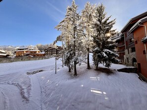 A snow-covered outdoor area with buildings and trees. - Duplex 6 pers, central location, parking, pets OK (La Plagne)