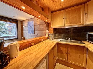 A kitchen with wooden cabinets, a sink, and a microwave.