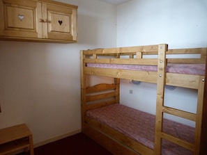 Cozy retreat with a bunk bed, nightstand, and cabinet.