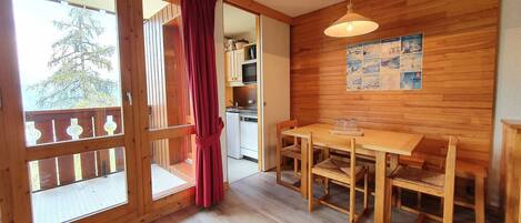 A wooden interior with a dining area, a kitchen, and a sliding glass door leading to an outdoor area.