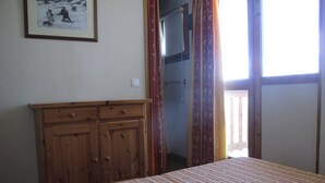 Un dormitorio con cama, armario de madera y un cuadro en la pared.
