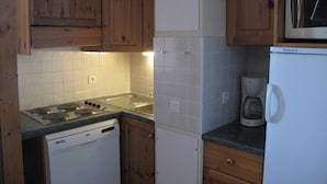 Una cocina con armarios de madera, un lavavajillas blanco, una estufa, un microondas y una cafetera.