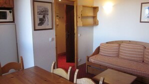 Una habitación acogedora con una mesa de comedor de madera, un sofá a cuadros, un microondas y un cuadro en la pared.