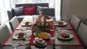 A dining table set with plates, glasses, and a bottle, surrounded by chairs, with a view of buildings through a glass door. - Feronia Guest House (Rome)