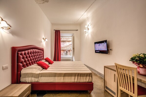A neatly arranged bedroom with a large bed, a television, a desk, and a chair. - Feronia Guest House (Rome)