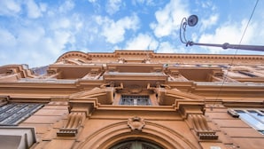 A building facade with ornate architectural details, including a prominent arched entrance with decorative ironwork and a window with intricate designs. - Feronia Guest House (Rome)
