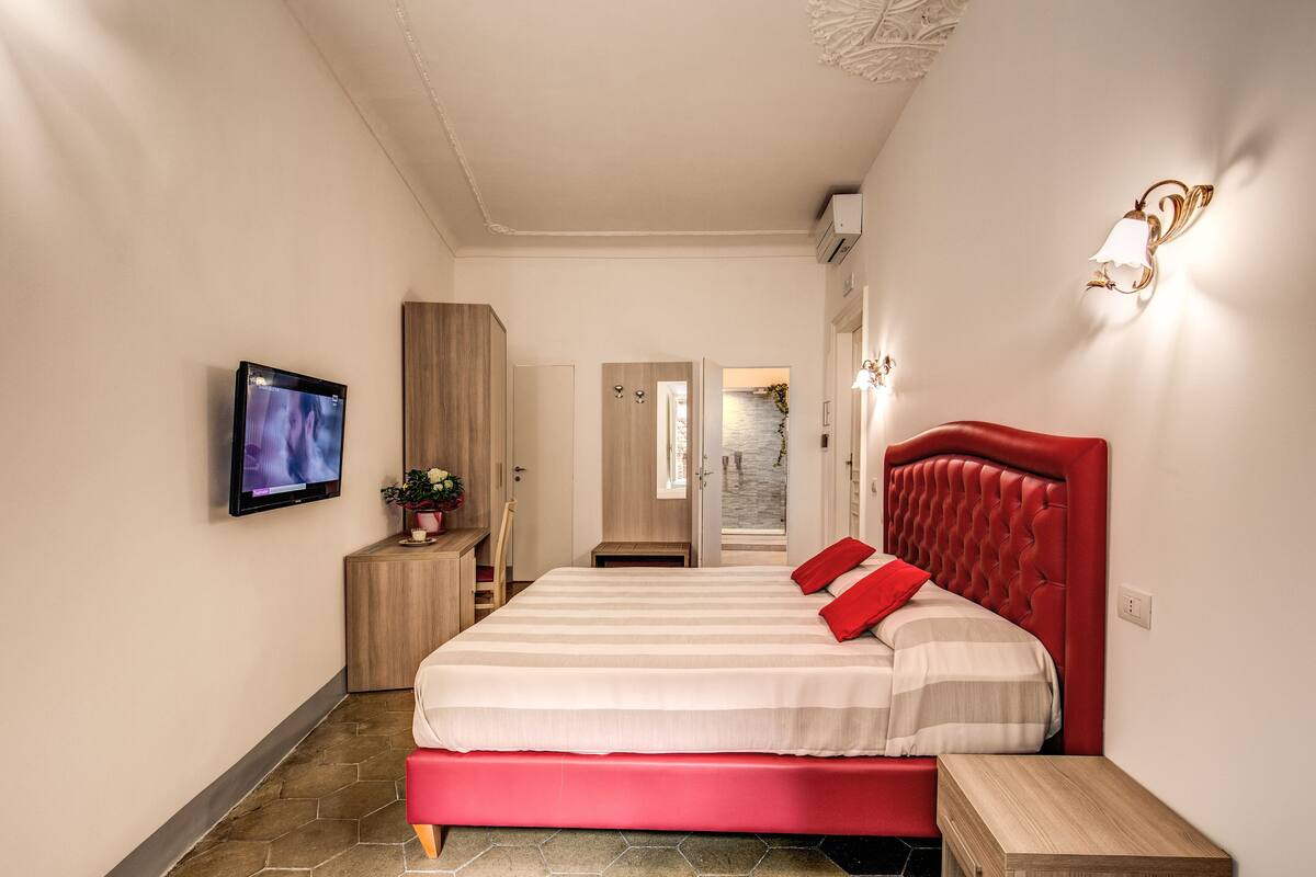 Ein modernes Schlafzimmer mit einem großen Bett, einem an der Wand befestigten Fernseher und einem Holzschrank.