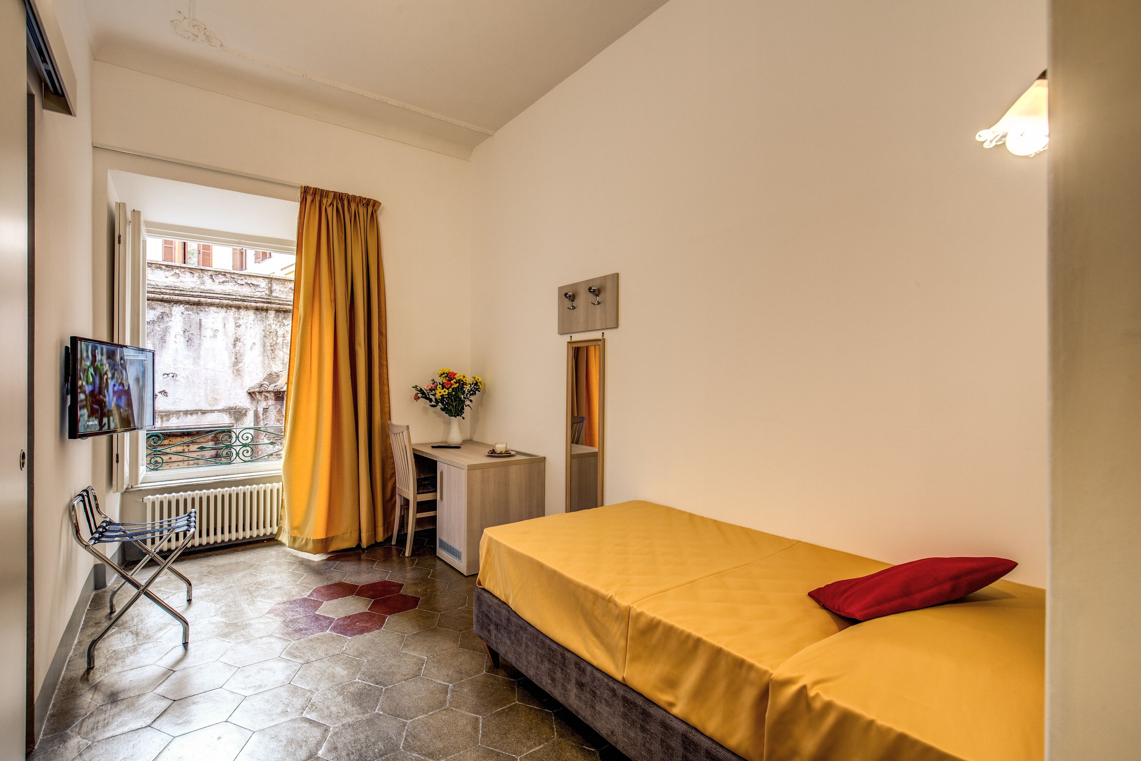 A room with a bed, a desk, a chair, and a window with curtains.