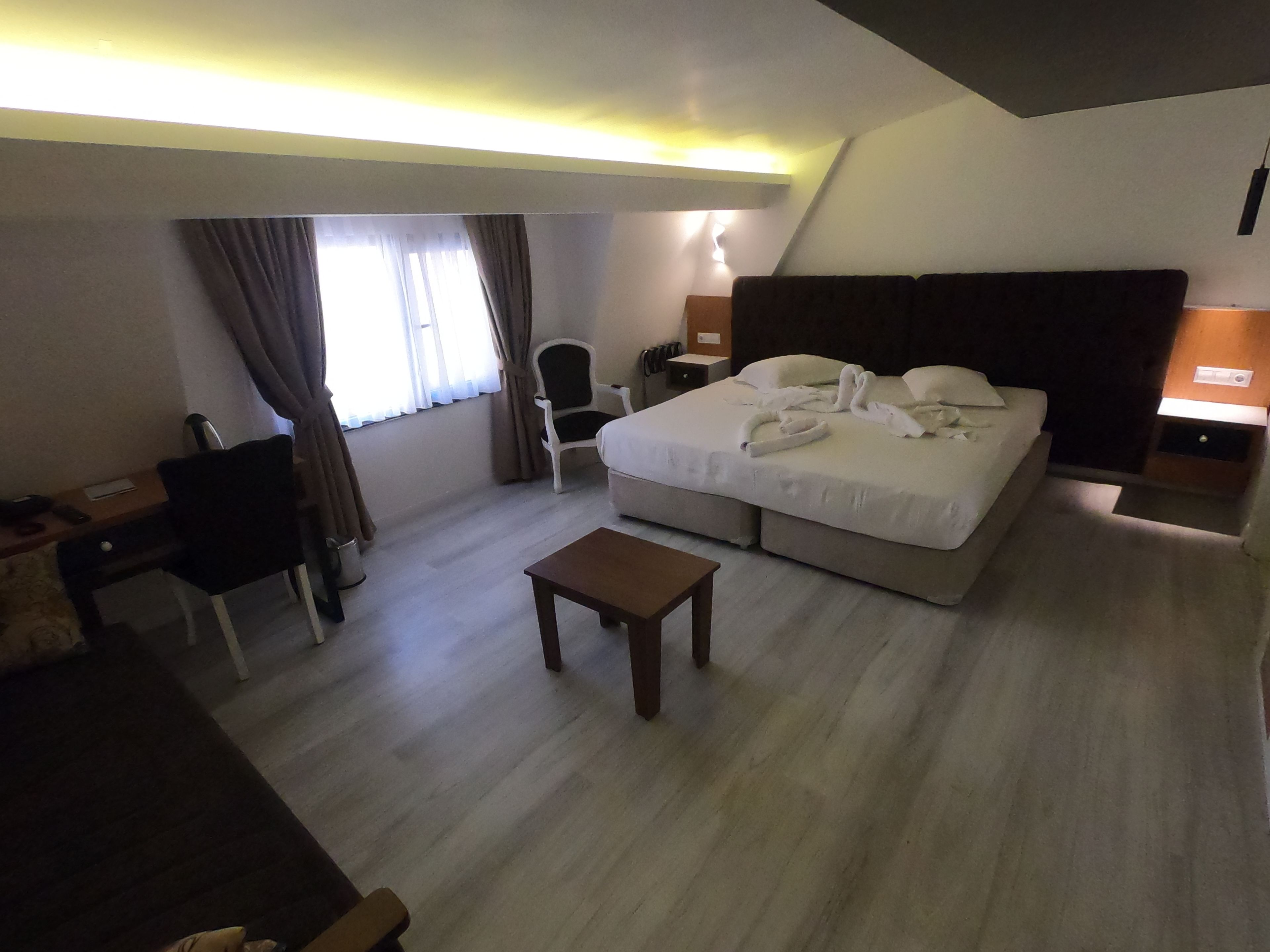Een hotelkamer met een bed, een bureau, een stoel, een bijzettafeltje en een nachtkastje.