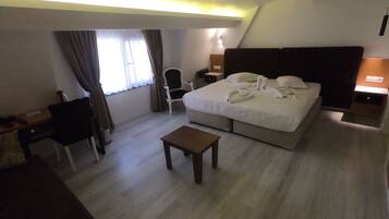 Een hotelkamer met een bed, een bureau, een stoel, een bijzettafeltje en een nachtkastje.