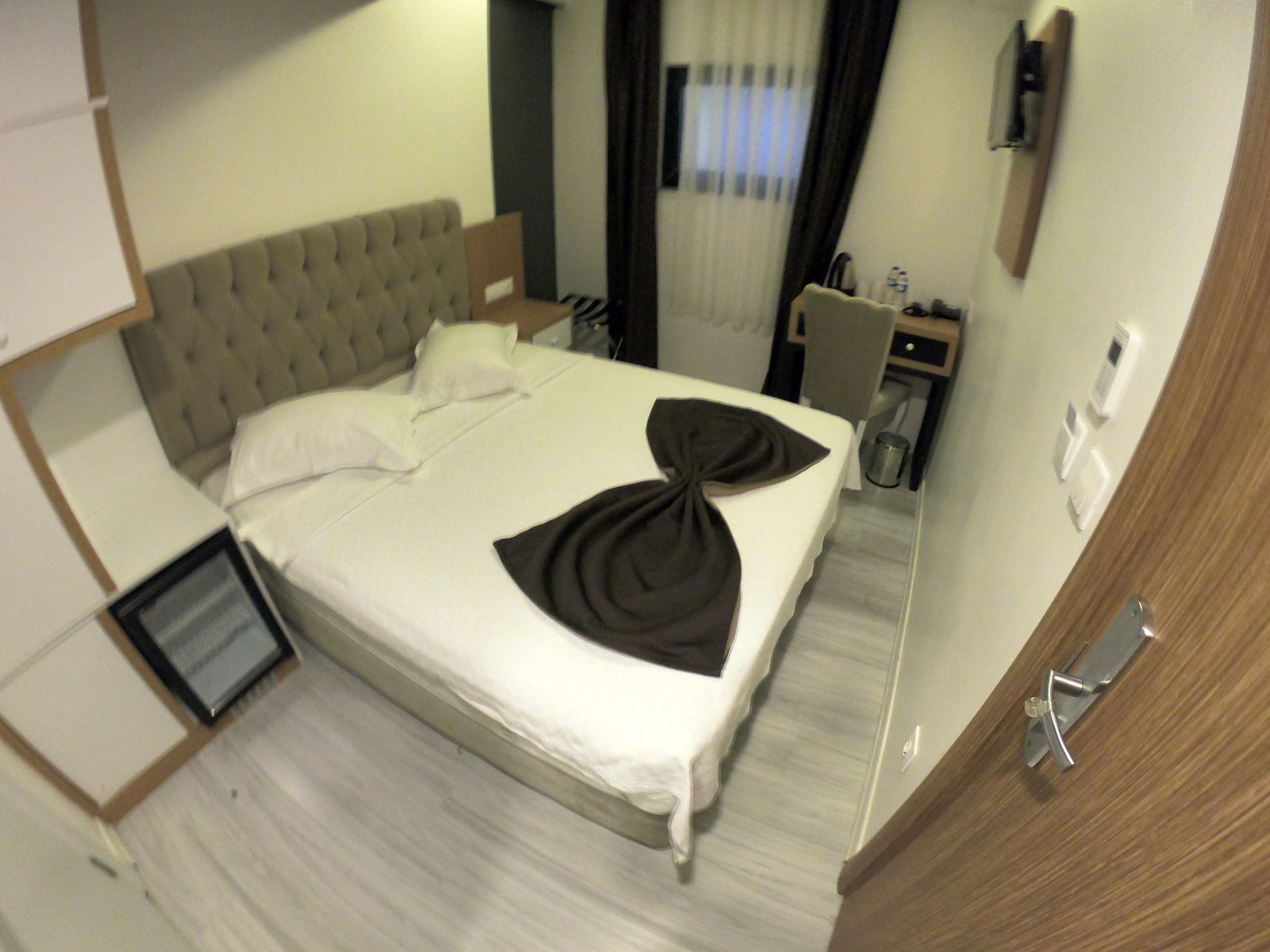 A hotel room with a large bed, a desk, and a chair.