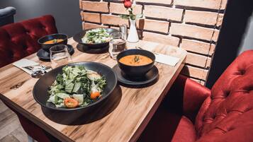 Ein Esstisch mit Salat, Suppe und einer Rose in einer Vase.