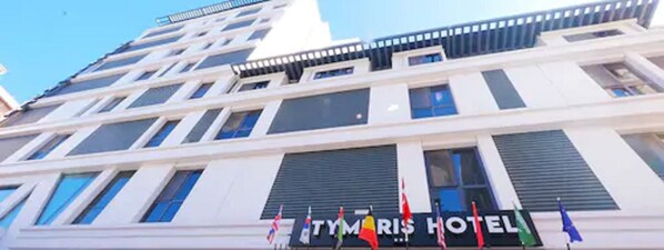 Un hotel de varios pisos con fachada moderna, con grandes ventanales y un cartel de hotel bien visible.