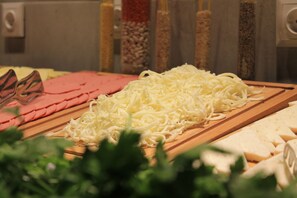 Una variedad de quesos y embutidos sobre una tabla de madera, destacando el queso rallado en primer plano.