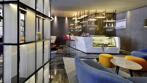 A modern bar area with a marble counter, red bar stools, and a display of bottles. - Mercure Taiyuan Changfeng Street (Taiyuan)
