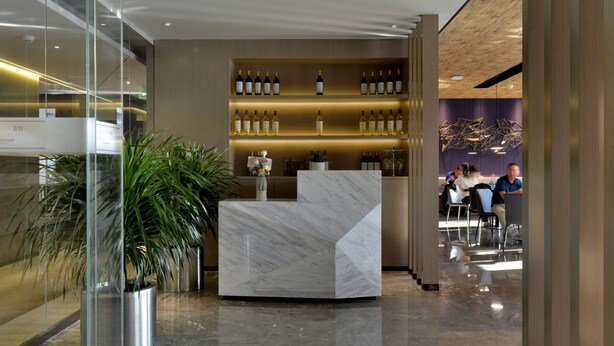 A modern reception area with a marble counter, a wine display, and a seating area with people. - Mercure Taiyuan Changfeng Street (Taiyuan)