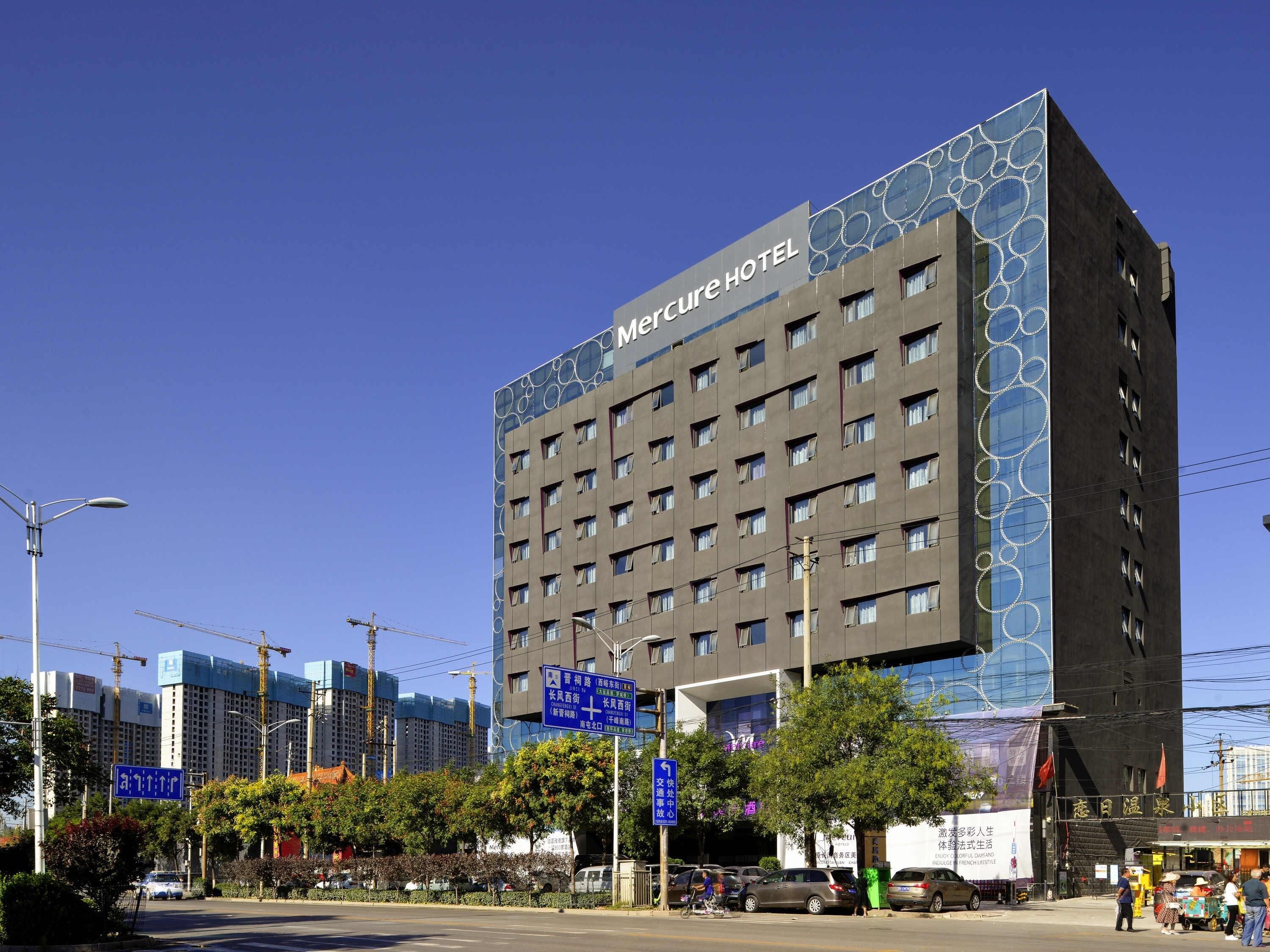 Un hotel con fachada moderna, varios pisos y un letrero llamativo.