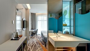 A modern hotel room with a large bathroom, a flat-screen TV, a dining area, and a bed. - ibis Styles Johor Iskandar Puteri (Gelang Patah)