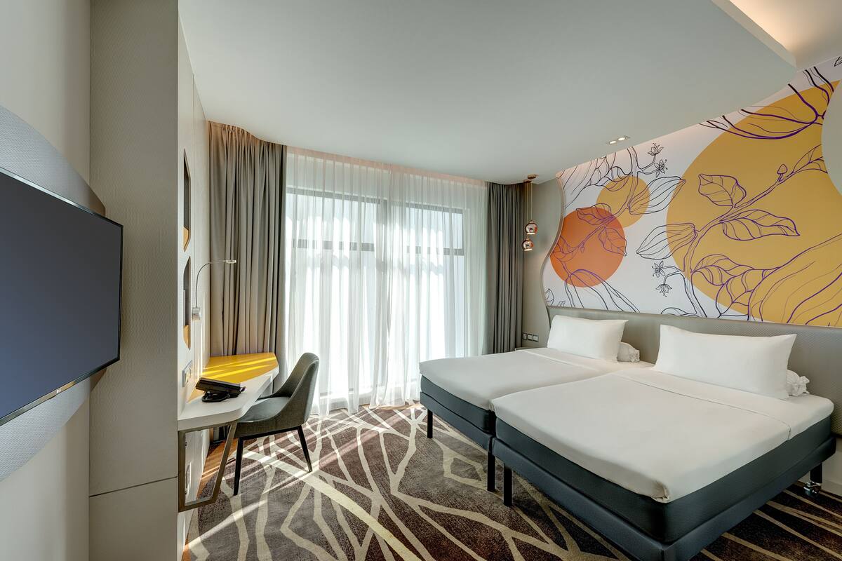 Een hotelkamer met een bed, een bureau, een stoel en een televisie.