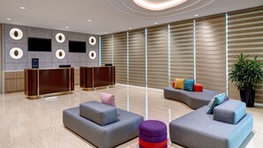 A modern lobby with a reception desk, seating areas, and a large plant. - ibis Styles Johor Iskandar Puteri (Gelang Patah)