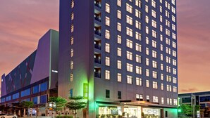 A multi-story hotel with a prominent "ibis Suites" sign, featuring a modern architectural design with a flat facade and numerous windows. - ibis Styles Johor Iskandar Puteri (Gelang Patah)
