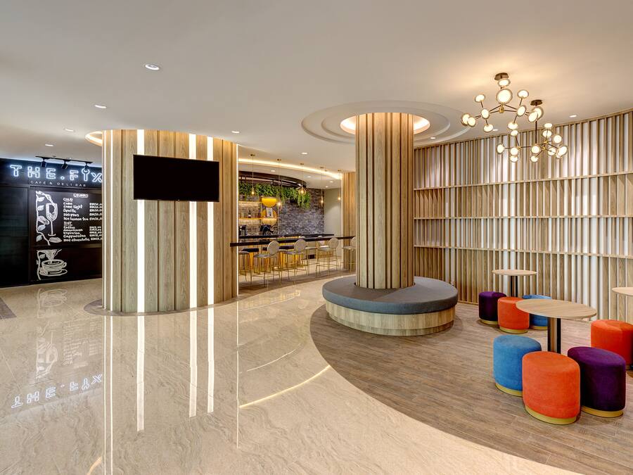 Un intérieur moderne avec un espace bar, des sièges agrémentés de poufs colorés et un mur en bois avec des lattes verticales.
