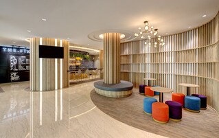 Un intérieur moderne avec un espace bar, des sièges agrémentés de poufs colorés et un mur en bois avec des lattes verticales.