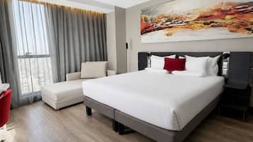 Et moderne hotelværelse med en stor seng, en sofa, en rød lænestol og et maleri på væggen.