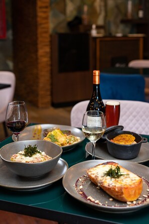 Una mesa de comedor con diversos platos, copas de vino y una botella.