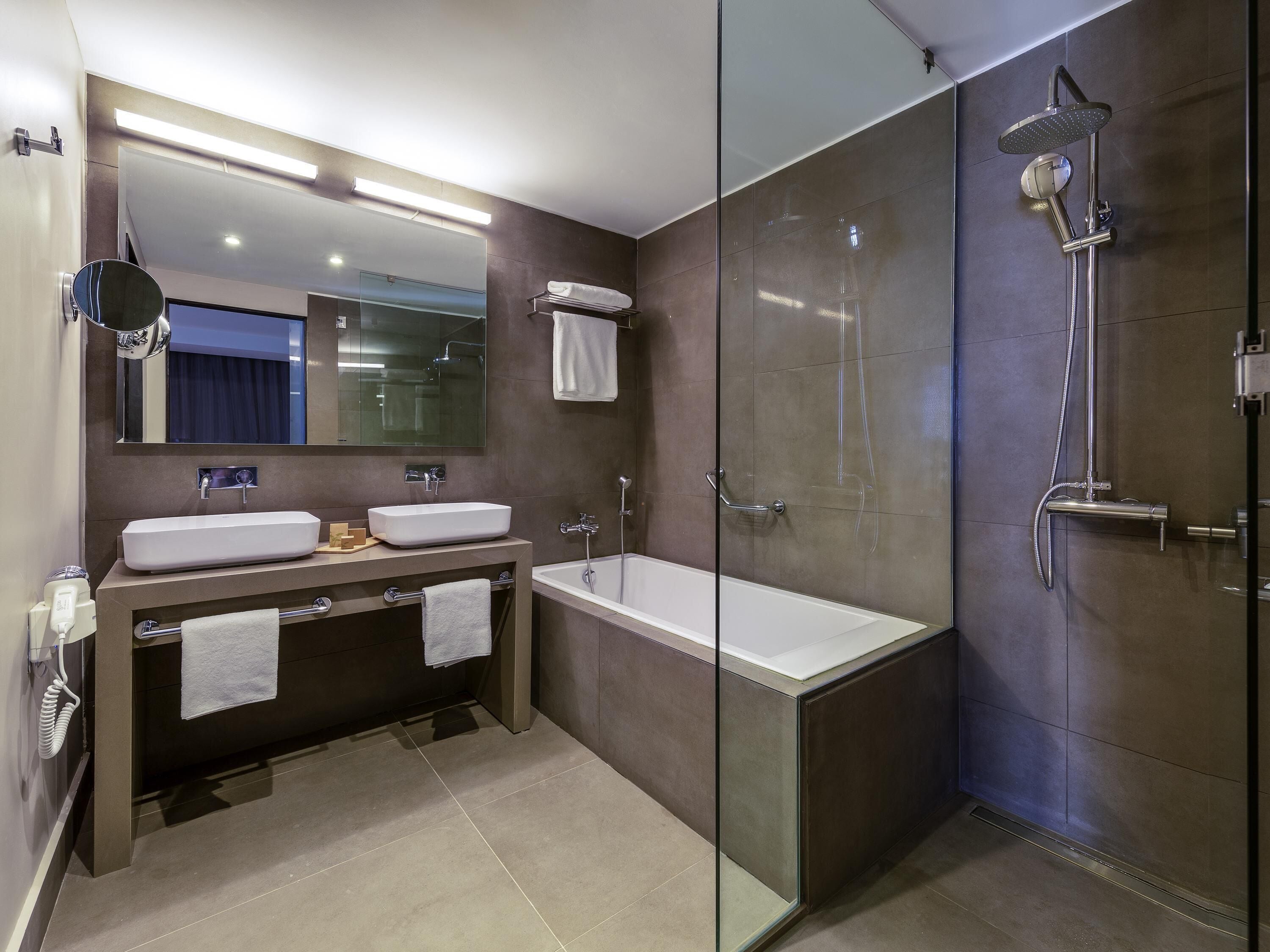 Un baño moderno con ducha de vidrio, tocador doble y un espejo grande.