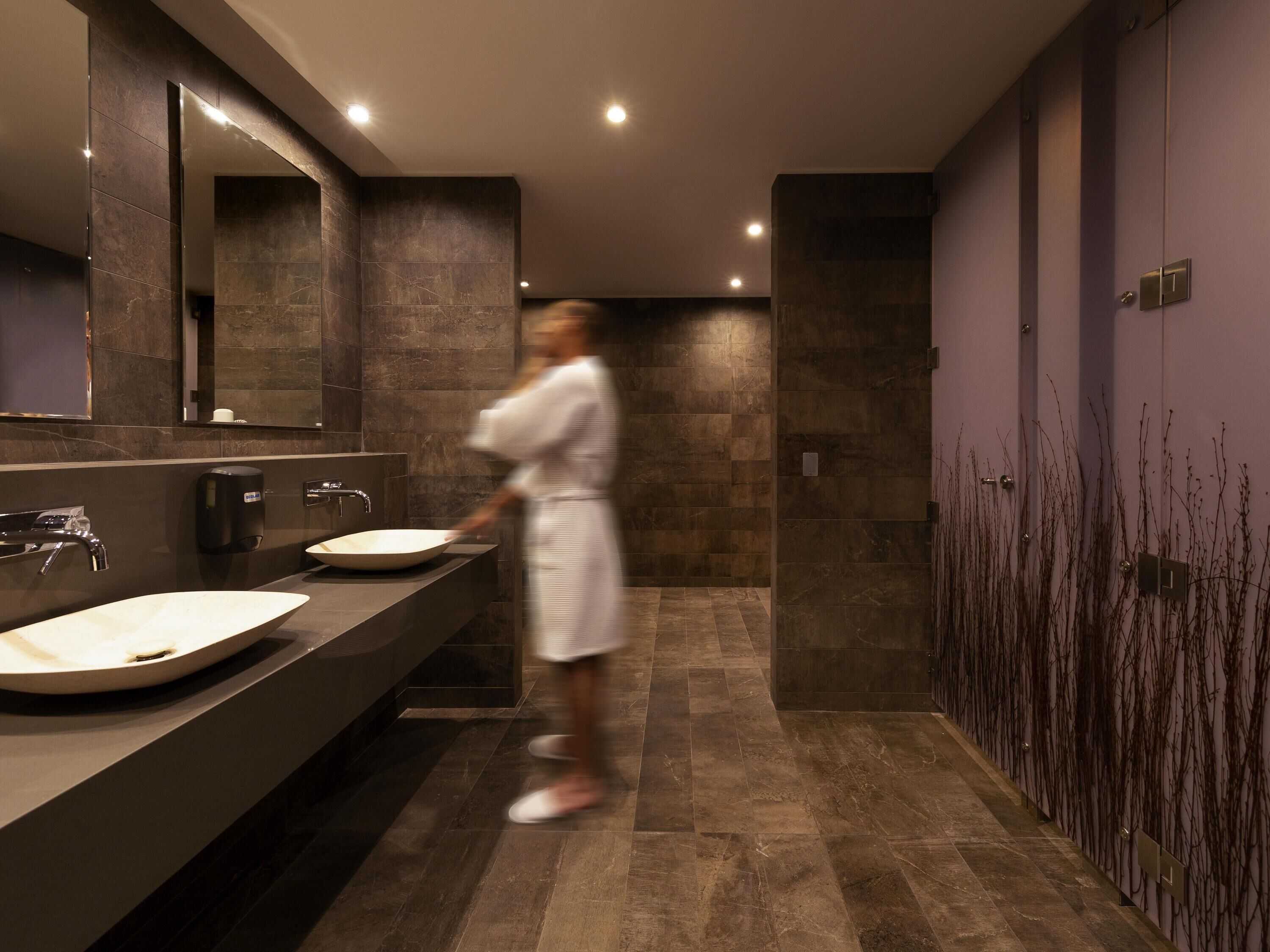 A modern bathroom with a large mirror, two sinks, and a walk-in shower.