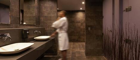 A modern bathroom with a large mirror, two sinks, and a walk-in shower.