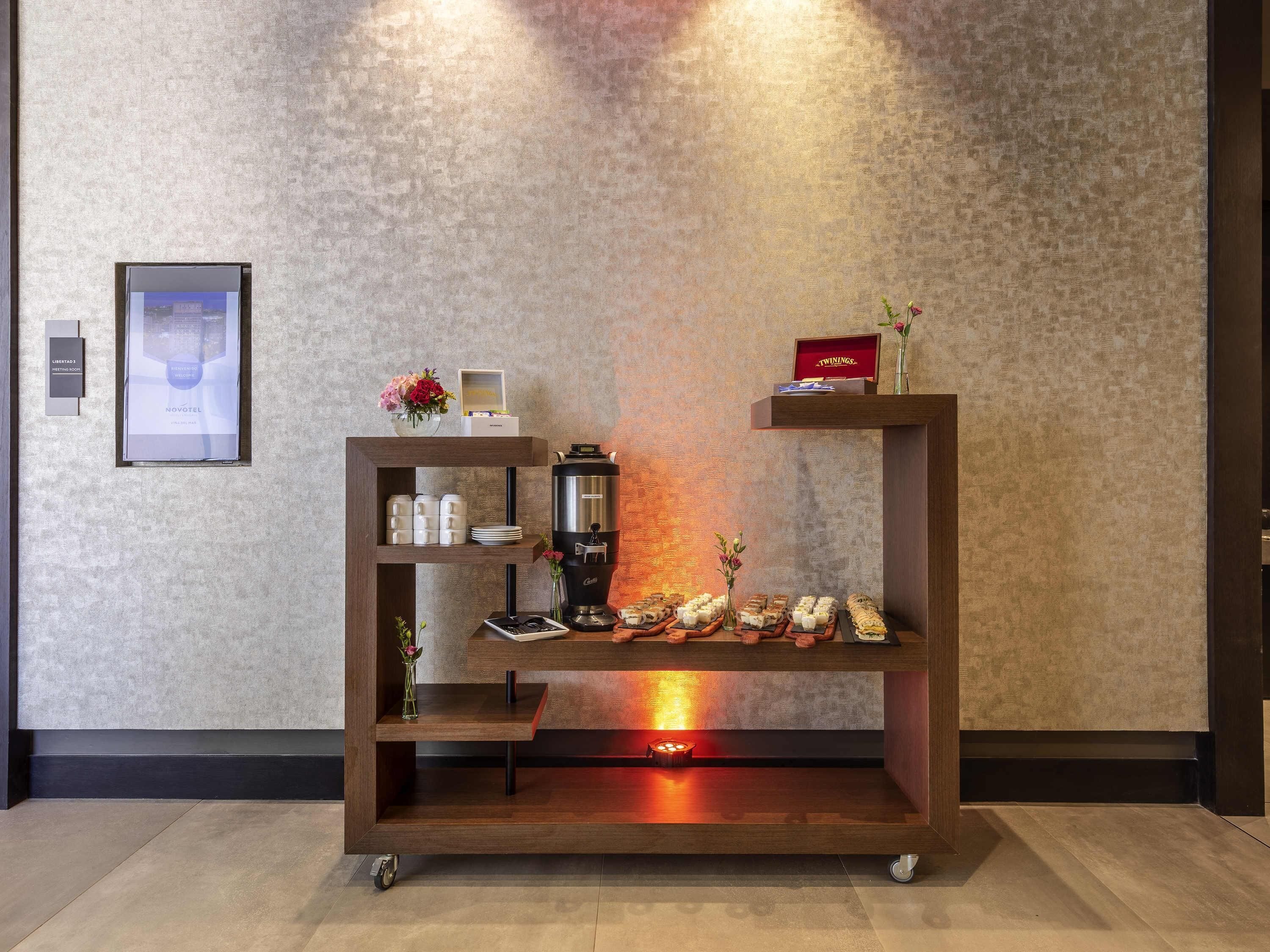 A modern reception desk with a coffee machine, a framed picture, and a vase of flowers.