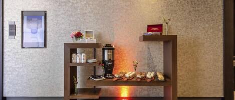 A modern reception desk with a coffee machine, a framed picture, and a vase of flowers.