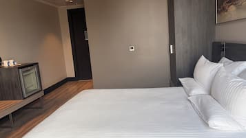 A modern hotel room with a large bed, a small television, and a painting on the wall.