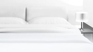 A bed with white linens, a nightstand with a lamp, and a plain wall. - Ibis Styles Douai Gare Gayant Expo (DOUAI)