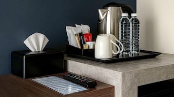 Ein Hotelzimmer-Schalter mit Taschentuchbox, Fernbedienung, Tablett mit Tasse, Wasserkocher und Wasserflaschen.